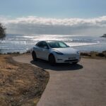 Une Tesla garée face à l'immensité de l'océan, un lieu idyllique pour profiter de la liberté de la conduite électrique. Offrez-vous un moment de détente avec vue sur l'horizon, tout en roulant dans le confort de votre véhicule électrique.